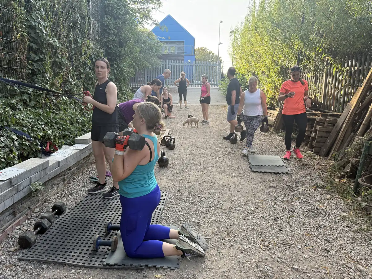 Members working through a circuit of dumbbells, kettlebells and bands along the path by the shed at Stave Hill