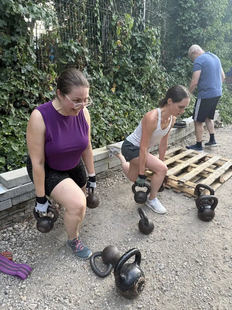 Two members doing kettlebell lunges beside the pallets at Stave Hill