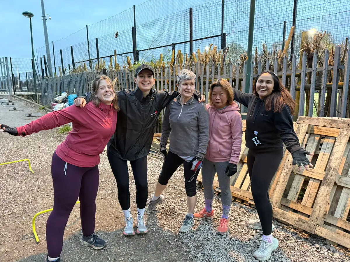 A small group of Bootcamp SE16 members laughing together before picking up weights