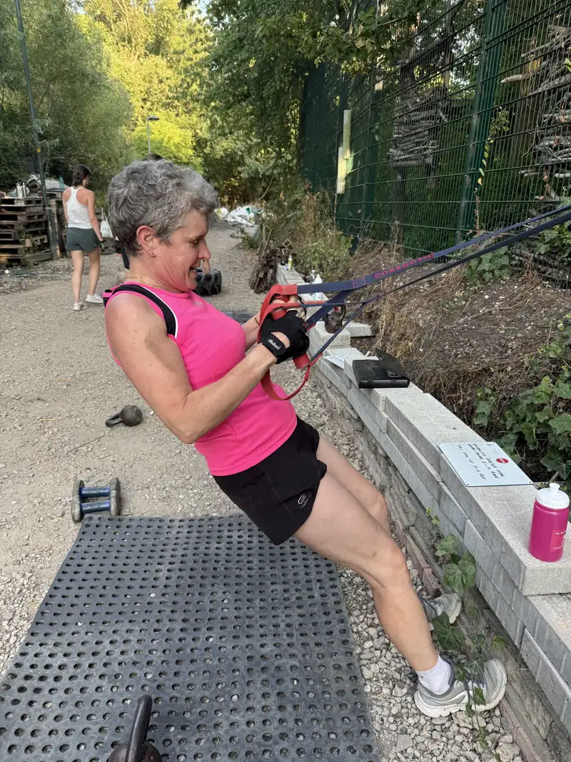 A member leaning back into a TRX row on the path at Stave Hill