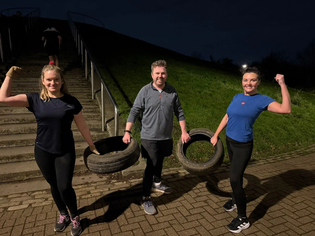 Three Bootcamp SE16 members flexing beside the tyres they have been carrying at the foot of the Stave Hill steps